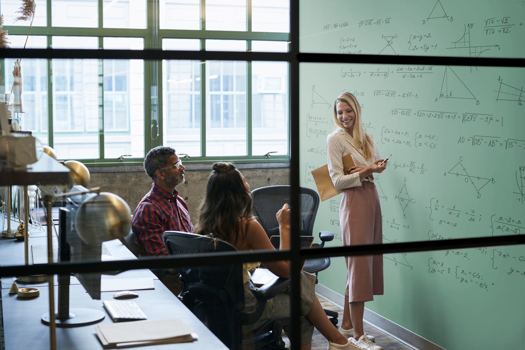Whiteboard paint in use — team presenting at a large green glass writing surface